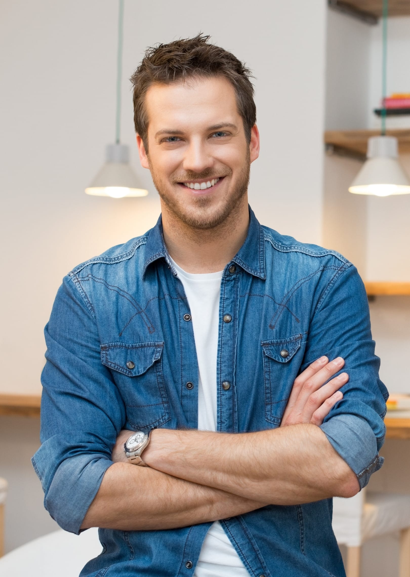 Smiling man crossing his arms in a room